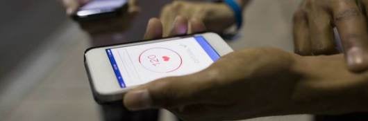 Two people taking their pulse while viewing a pulse monitor on their smartphones